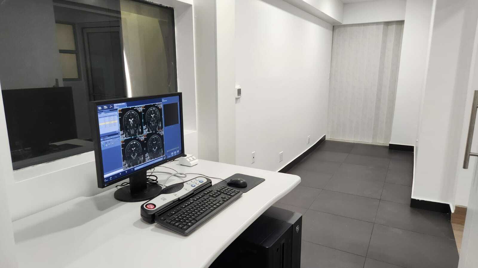 Área de control de Radiocare con monitores que muestran imágenes médicas y ventana a sala de diagnóstico